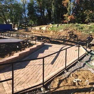 A metal fence is surrounding a brick walkway.