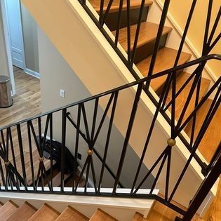 A staircase with a black railing and wooden steps in a house.