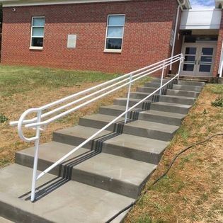 A set of stairs with a white railing and a brick building in the background.