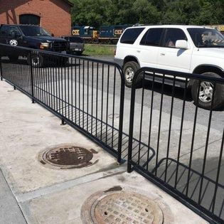 A white suv is parked behind a black metal fence.