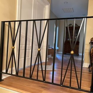 A wrought iron railing is sitting on top of a wooden staircase in a living room.