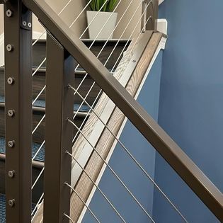 A close up of a stair railing with stainless steel wire.