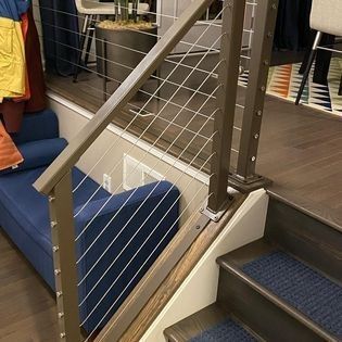 A staircase with a wire railing and a blue couch in a living room.
