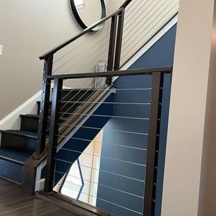 A staircase with a stainless steel railing and a mirror on the wall.