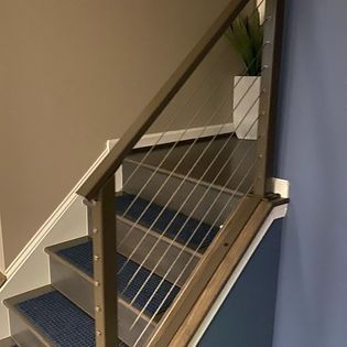 A staircase with a wire railing and a blue carpet.