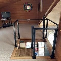 A wooden staircase with a black railing and a tv on the wall.