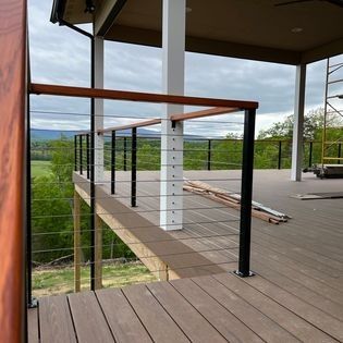 A wooden deck with a metal railing and a view of the mountains.