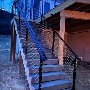 A set of stairs leading up to a deck with a wire railing.