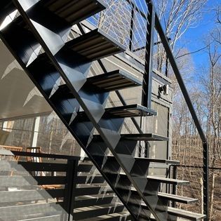 A black metal staircase with wooden steps and a wire railing