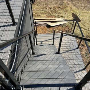 A set of stairs leading up to a deck with a metal railing.