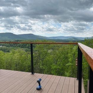 A drill is sitting on a wooden deck overlooking a forest.