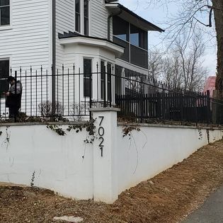 A white house with a black fence and a pillar with the number 7 on it.