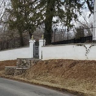 A white wall with a gate and steps next to a road.
