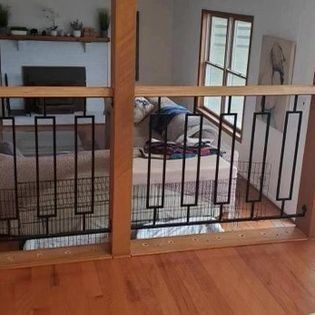 A dog is laying on a couch in a living room behind a fence.