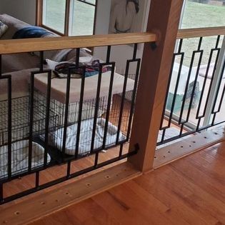 A dog cage is behind a metal railing in a living room.