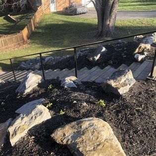 A set of stairs leading up to a house surrounded by rocks and mulch.