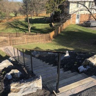 A set of stairs leading up to a house with a fence in the background.