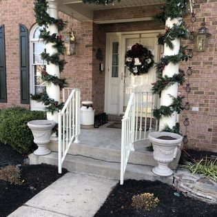 A brick house with a porch decorated for christmas