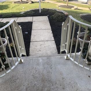 A set of stairs leading up to a walkway with a white railing.