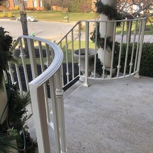 A white railing on a porch with stairs leading up to it.