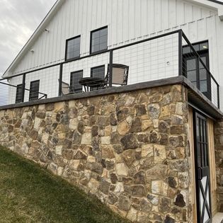 A white house with a stone wall and a balcony.