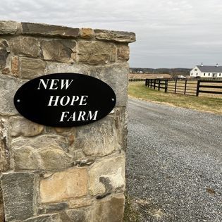 A sign on a stone wall says new hope farm