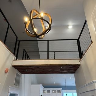 A room with a balcony and a chandelier hanging from the ceiling.