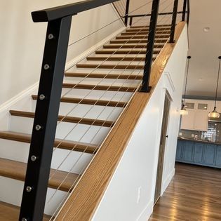A staircase with a black railing and wooden steps in a house.