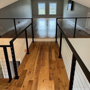A hallway with wooden floors and a black railing in a house.