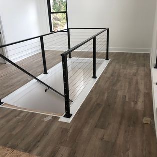 A staircase with a black railing and a wooden floor in a house.