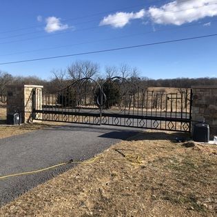 A wrought iron gate is sitting on the side of a road.