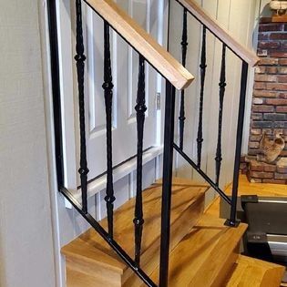 A wooden staircase with a black railing and a wooden handrail.