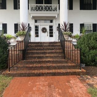A white house with a brick walkway and stairs leading up to the front door.
