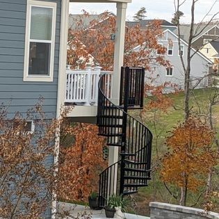 A spiral staircase is attached to the side of a house.