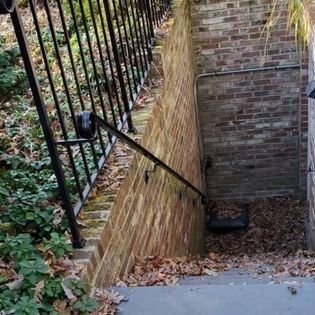 A brick wall with stairs leading up to it and a wrought iron railing.