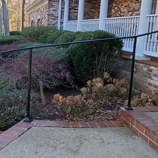 A black railing is sitting on the sidewalk in front of a house.