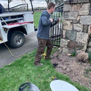 A man is working on a fence next to a truck.