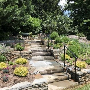 A set of stone stairs leading up to a stone wall in a garden.