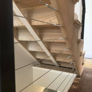 A wooden staircase with a stainless steel railing in a house.