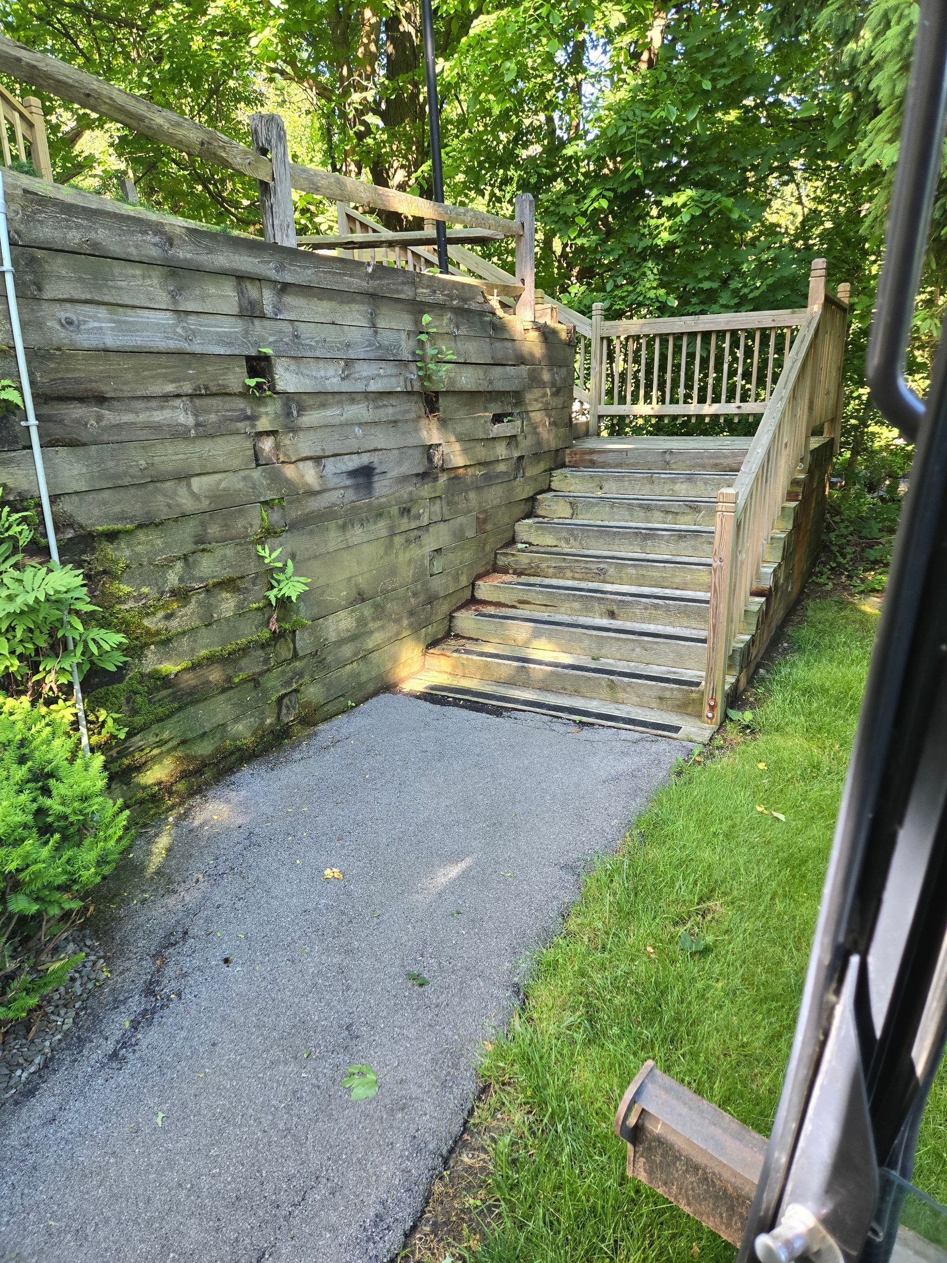 Stone steps with significant damage, a brick wall to the right, and a metal railing to the left.