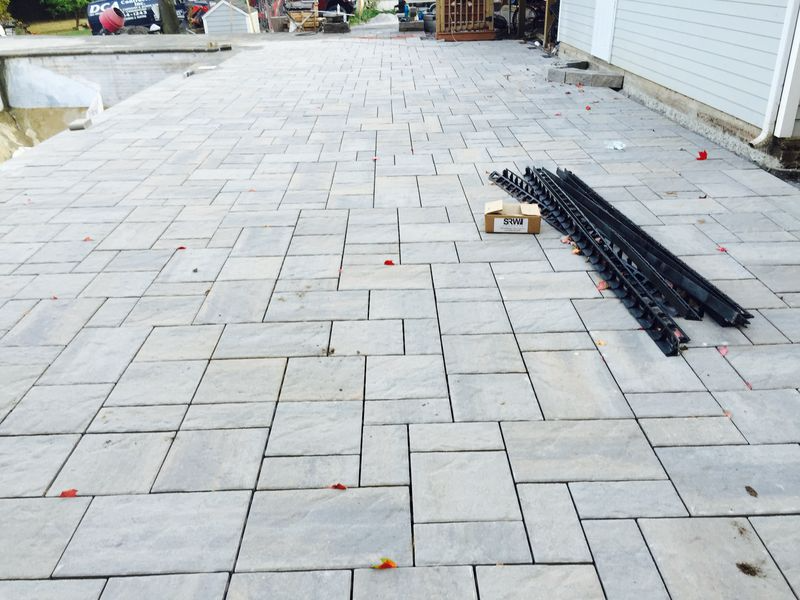 Newly laid gray stone pavers on a patio with decorative black railing pieces.
