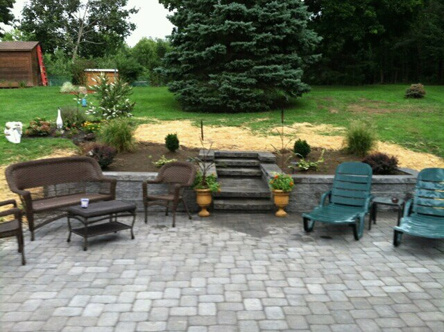 Patio with seating, steps, and landscaping in a backyard.