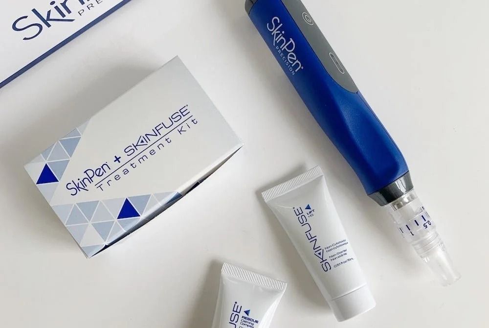 SkinPen microneedling device with Skinfuse treatment kit and tubes on a white surface.
