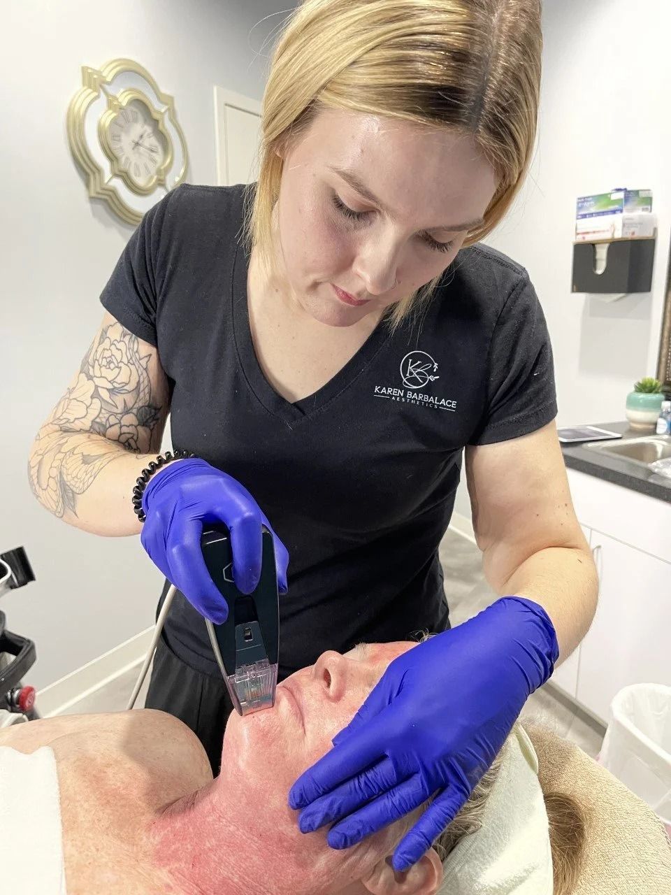Woman receiving facial treatment; technician using handheld device near mouth.