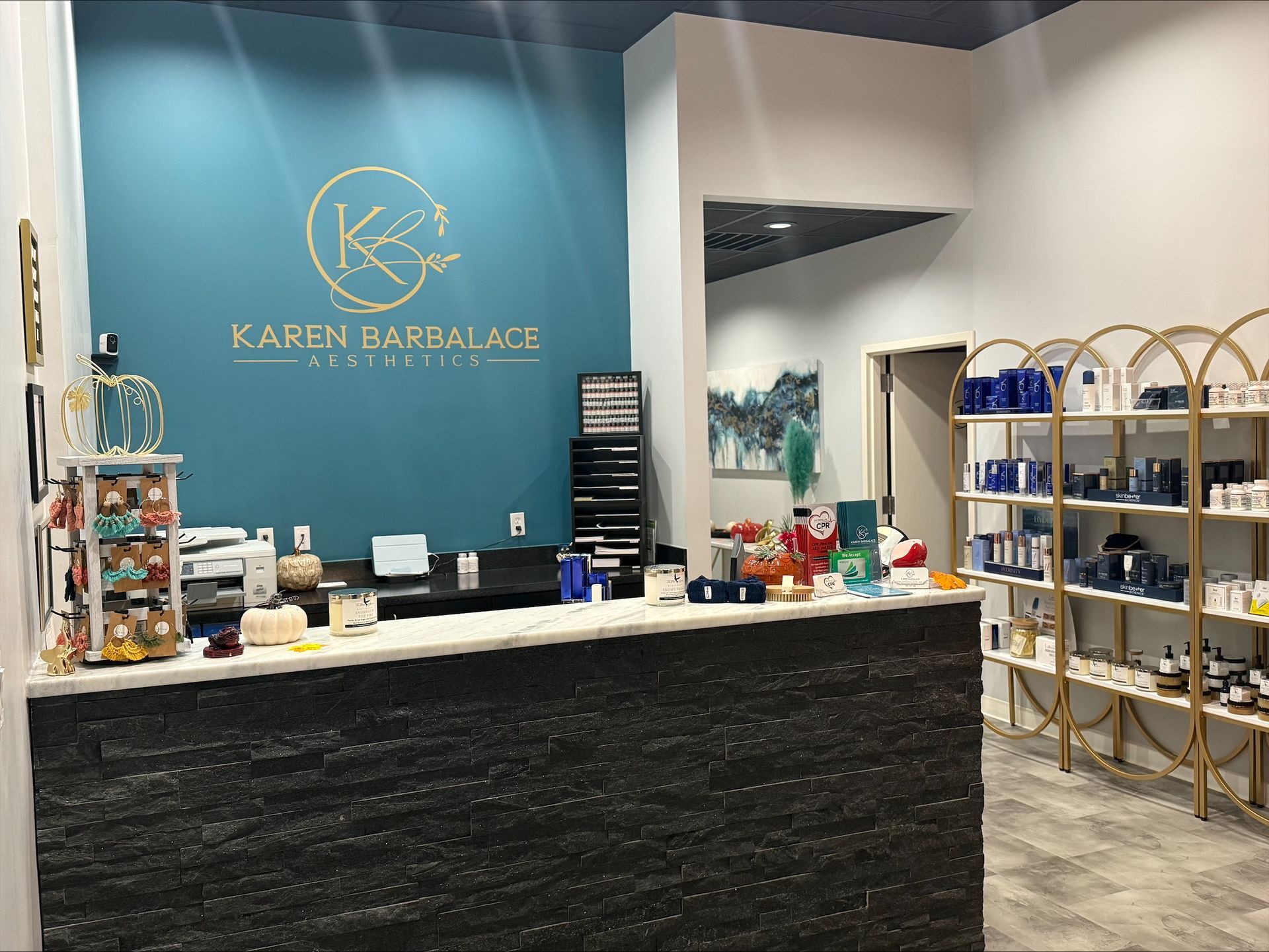 Reception area with teal accent wall, marble-look counter, and two velvet chairs.