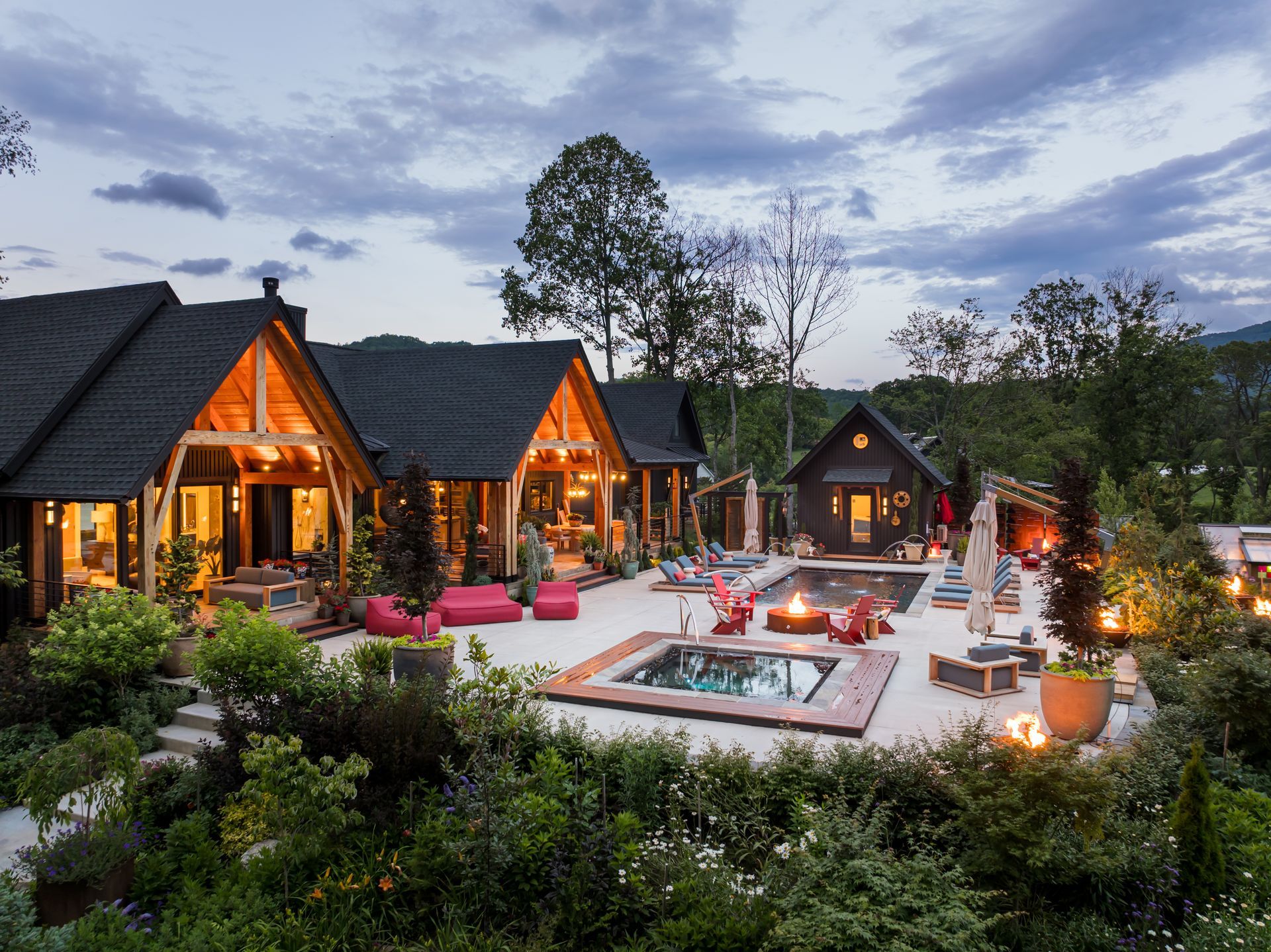 Cozy cabins with a lit patio, outdoor fire pit, and lounge area at dusk amid greenery