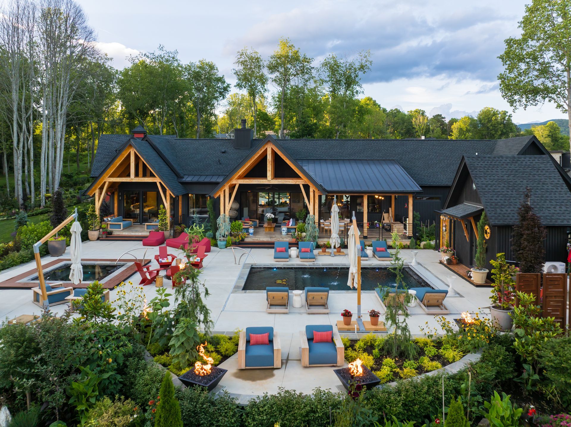 Modern lodge with outdoor patio seating, fire pits, and colorful chairs in a forest setting