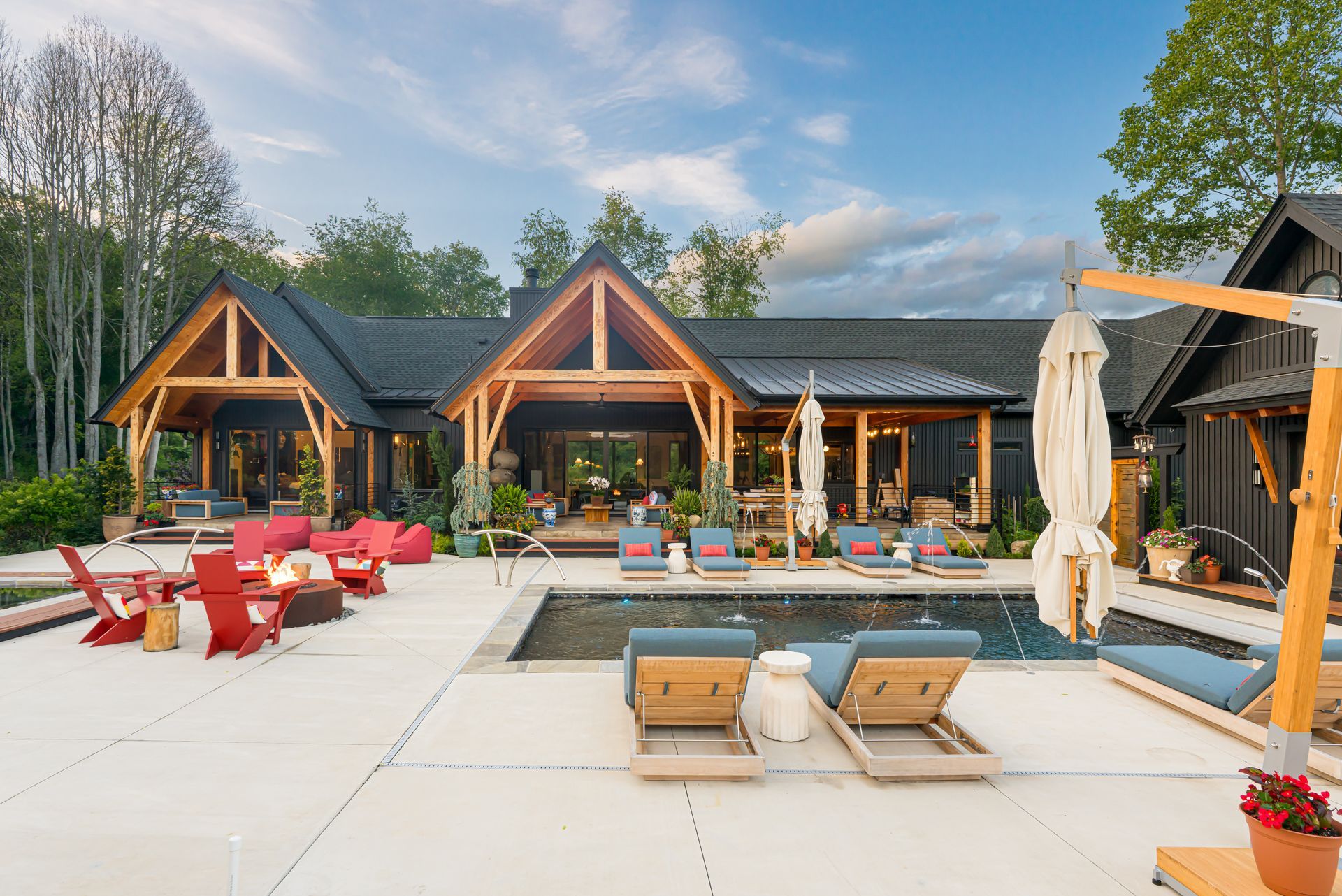 Modern cabin patio with red lounge chairs, pool, and mountain views under a cloudy sky