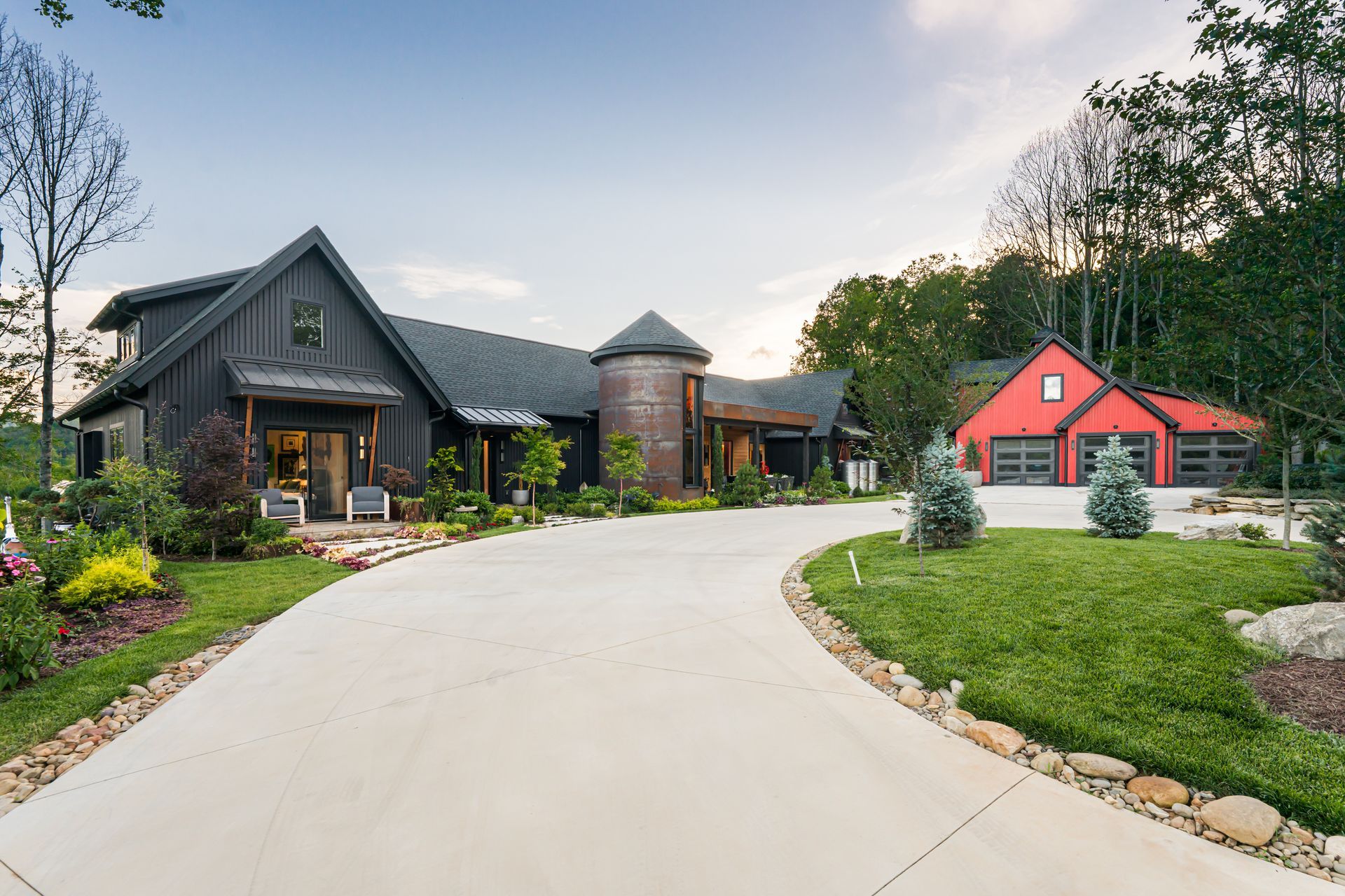 Curved driveway leading to a modern rustic house and red garage in a landscaped neighborhood