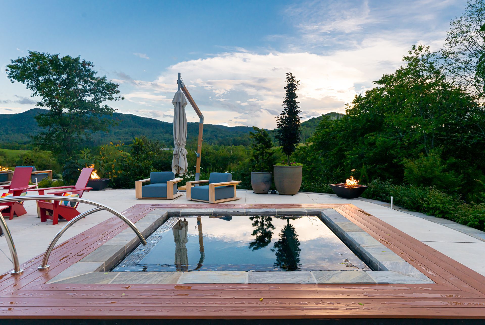 Poolside patio with red chairs, lounge chairs, and mountain views at sunset